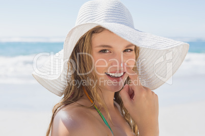 Beautiful girl putting spf on nose on the beach smiling at camer