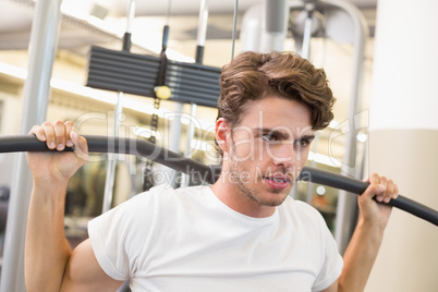 Fit man using weights machine for arms