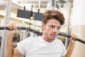 Fit man using weights machine for arms