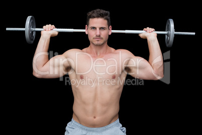 Serious handsome crossfitter lifting up barbell behind head