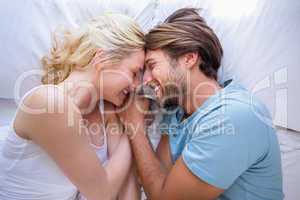 Cute couple relaxing on bed smiling at each other