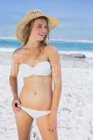 Beautiful happy blonde on the beach in white bikini and sunhat