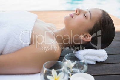 Peaceful brunette lying with eyes closed on a towel