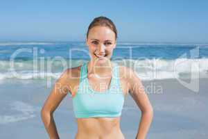 Fit woman standing on the beach with hands on hips
