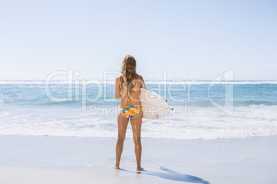 Beautiful surfer girl standing on the beach with her surfboard