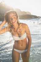 Beautiful laughing blonde in white bikini at the beach with wet