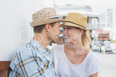 Young hip couple sitting on bench about to kiss