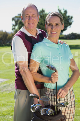 Golfing couple standing smiling at camera