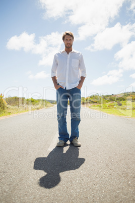 Handsome casual man standing on a road smiling at camera