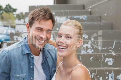 Hip young couple sitting on steps smiling at camera