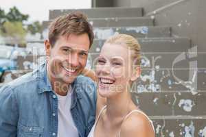 Hip young couple sitting on steps smiling at camera