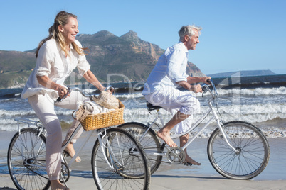 Smiling couple riding their bikes on the beach