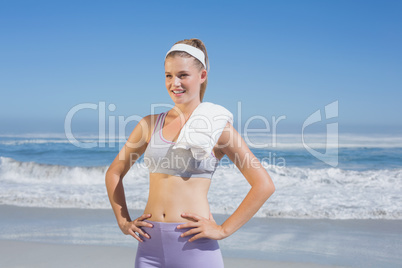 Sporty happy blonde standing on the beach with towel