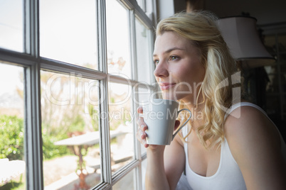 Pretty blonde sitting by the window having coffee