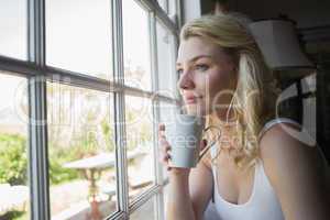 Pretty blonde sitting by the window having coffee