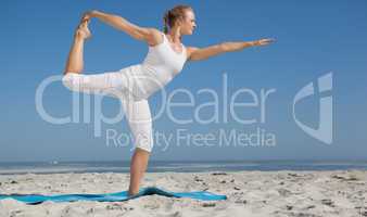 Blonde woman standing in warrior pose on beach