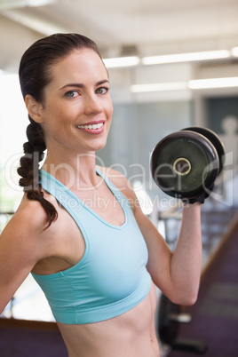 Smiling woman lifting heavy dumbbells