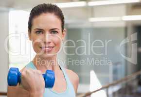 Smiling woman lifting blue dumbbell