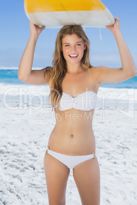 Pretty surfer girl holding her surfboard on the beach