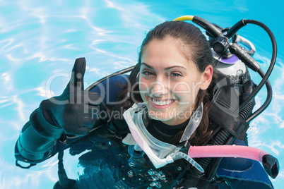 Smiling woman on scuba training in swimming pool showing thumbs