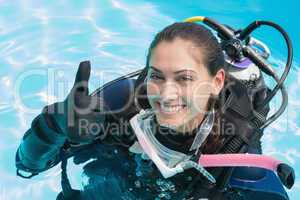 Smiling woman on scuba training in swimming pool showing thumbs