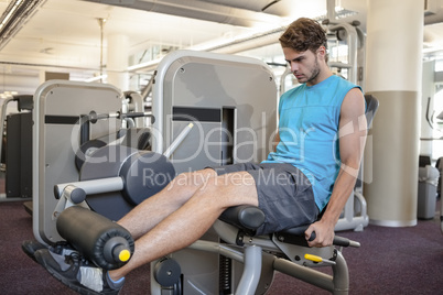 Focused man using weights machine for legs