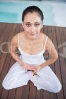 Peaceful brunette in white sitting in lotus pose