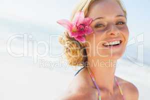 Gorgeous blonde in bikini smiling at camera on the beach