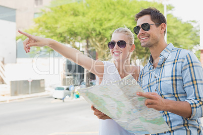 Young tourist couple consulting the map and pointing