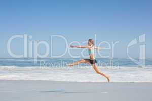 Fit woman jumping gracefully on the beach