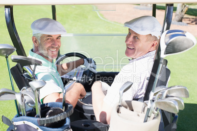 Golfing friends driving in their golf buggy smiling at camera