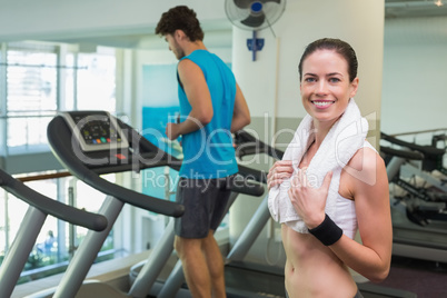 Fit brunette smiling at camera with towel around shoulders