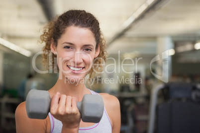 Fit woman smiling at camera lifting dumbbell Fit woman smiling at camera lifting dumbbell