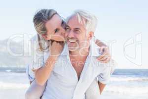 Man giving his smiling wife a piggy back at the beach