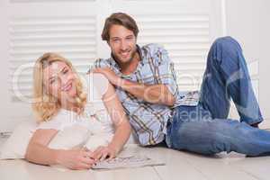 Happy couple sitting on floor doing crossword