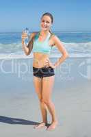 Fit woman standing on the beach holding water bottle