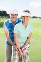 Golfing couple putting ball together smiling at camera