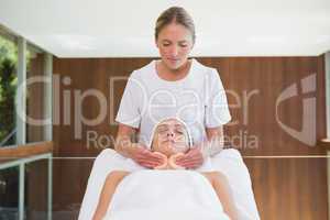 Peaceful brunette getting facial from beauty therapist