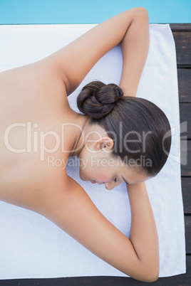 Peaceful brunette lying poolside on towel