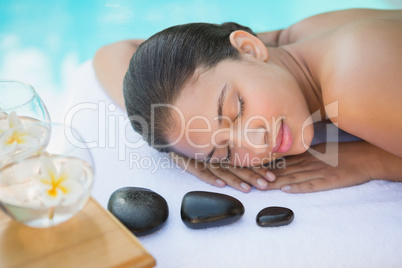 Smiling brunette lying on towel having a hot stone massage