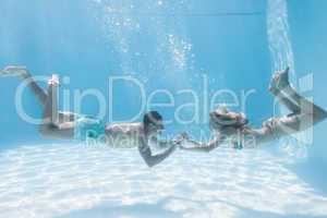 Cute couple holding hands underwater in the swimming pool