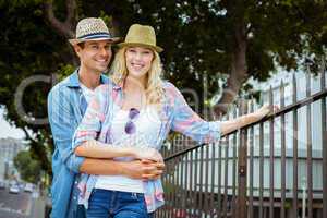 Hip young couple smiling at camera by railings