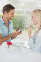 Man surprising his girlfriend with a proposal in cafe