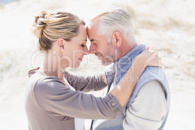 Happy hugging couple on the beach looking at each other