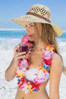 Pretty blonde in floral garland sipping cocktail on the beach