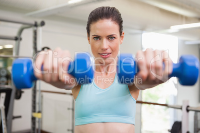 Smiling woman lifting blue dumbbells