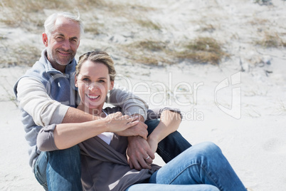 Attractive couple smiling at camera on the beach