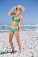 Pretty laughing woman in bikini on beach wearing sunhat