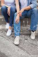 Hip young couple in denim sitting on steps