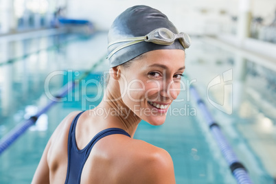 Pretty swimmer by the pool smiling at camera